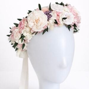 Preserved flower crown with blush, ivory, and pastel flowers arranged on a mannequin head against a white background