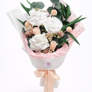 Elegant preserved flower bouquet with white roses, blush accents, eucalyptus leaves, and soft peach ribbon on a white background