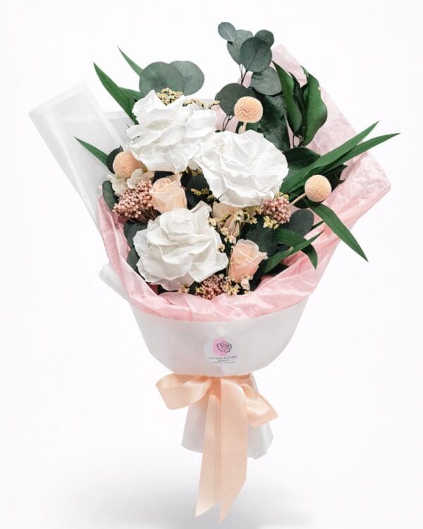 Elegant preserved flower bouquet with white roses, blush accents, eucalyptus leaves, and soft peach ribbon on a white background
